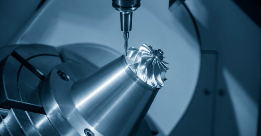 A close-up of a milling tool cutting a shiny metal turbine part and creating a precise turbocharger component.