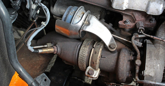 A diesel engine showcasing a turbocharger system with an actuator. The components have small rust spots on them.