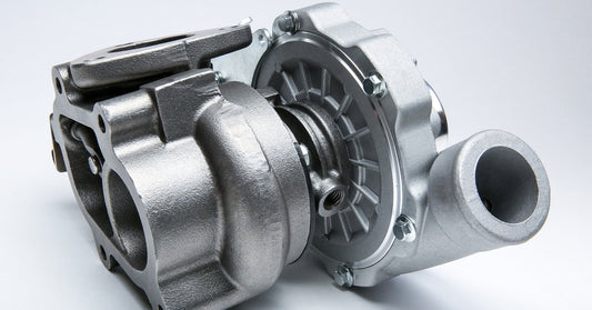 A new turbocharger showcases its parts, like the air outlet and compressor, while placed against a white background.