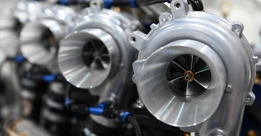 Close-up of turbochargers mounted on an engine, highlighting compressor housing, piping, and fittings detail.