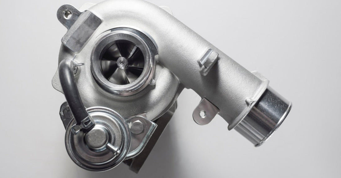 New car turbocharger isolated on a white background, showing the metal housing, turbine opening, and fittings.