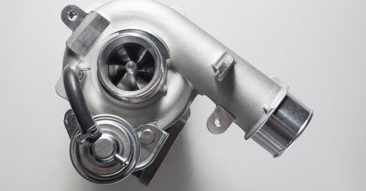 New car turbocharger isolated on a white background, showing the metal housing, turbine opening, and fittings.