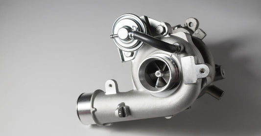 New turbocharger isolated on white, showing compressor housing, turbine section, and mounting flange in detail.