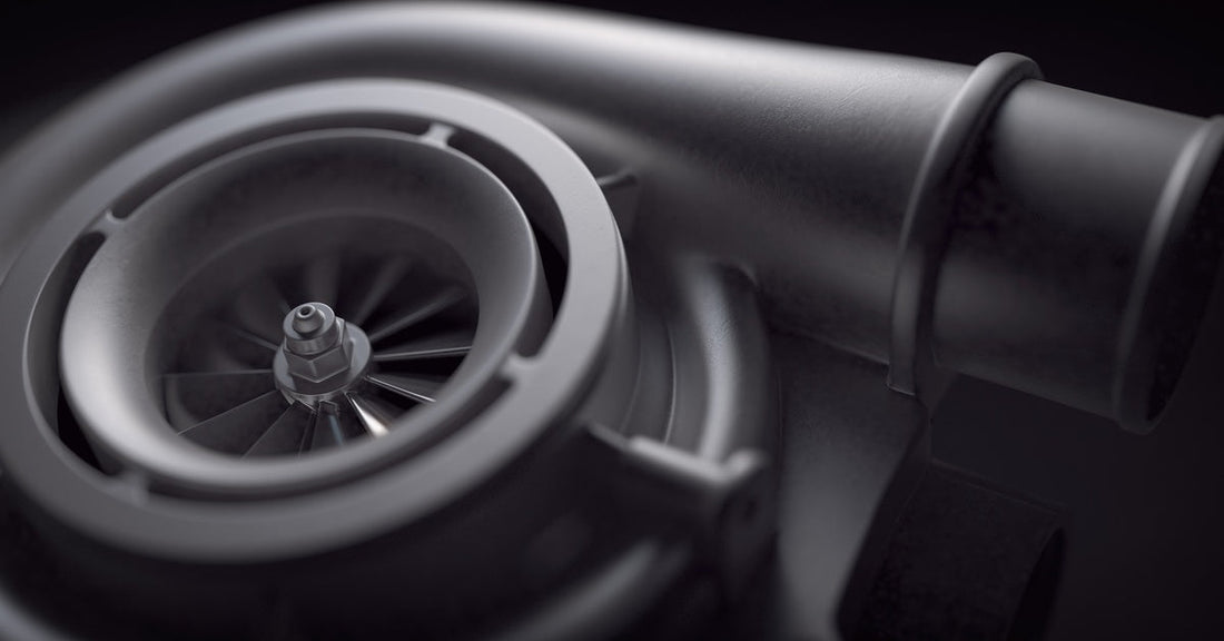Close-up of a metallic turbocharger with visible compressor blades, circular housing, and a smooth pipe outlet design.